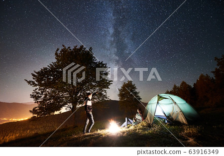 Couple tourists resting at night camping under stars Couple tourists resting at night camping under stars 63916349
