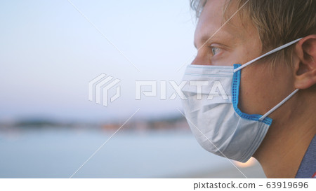 Young man in medical mask meditates on the beach. Coronavirus epidemic 63919696