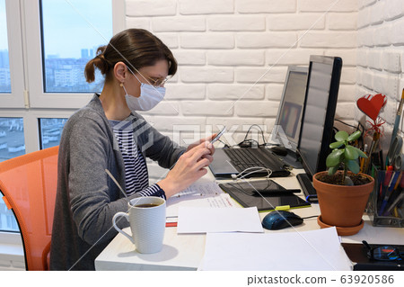 A sick girl in a medical mask at home communicates 63920586