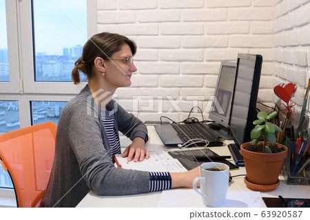 Happy girl working remotely at home at a personal Happy girl working remotely at home at a personal 63920587