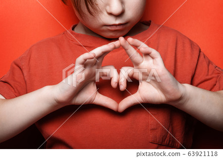 Sad boy shows a heart symbol at his chest Sad boy shows a heart symbol at his chest 63921118