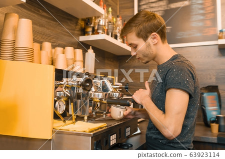 Young male coffee shop worker making coffee with machine Young male coffee shop worker making coffee with machine 63923114
