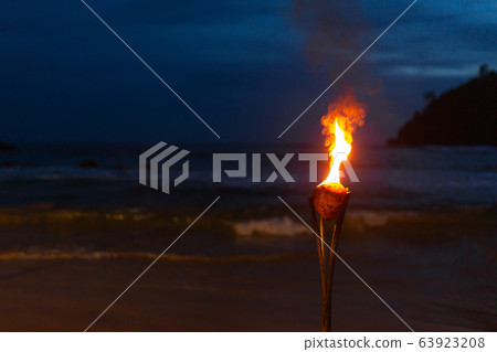 Burning torch on the sandy beach of the ocean 63923208