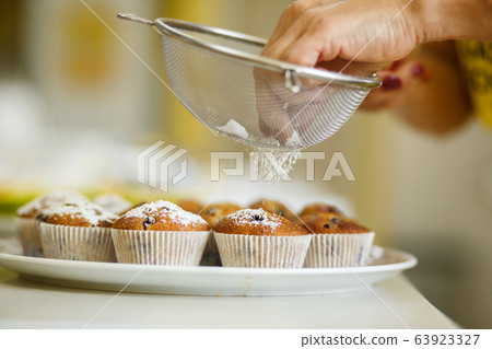 Confectioner sprinkles freshly baked muffins with Confectioner sprinkles freshly baked muffins with 63923327
