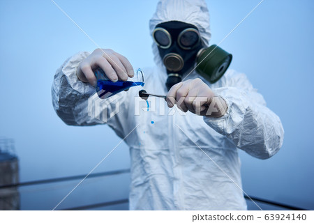 Worker scientist wearing protective coverall and gas mask doing ecological tests on the roof 63924140