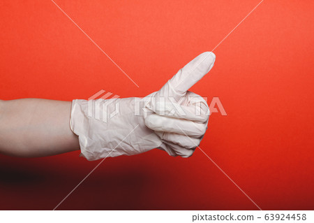 Child hand in big medical glove shows thumb up on red background 63924458