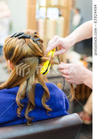 professional hairdresser using curling iron hair 63924494