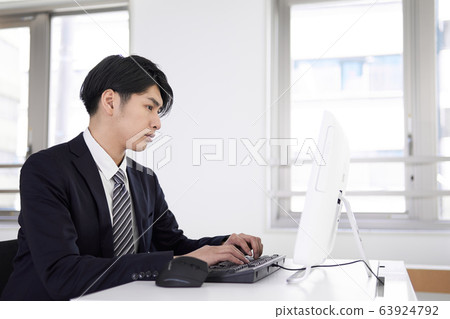 使用嚴肅的表情的個人計算機上工作的日本男性商人 使用嚴肅的表情的個人計算機上工作的日本男性商人 63924792