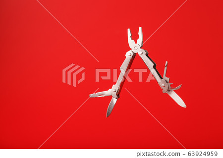Multitool is a multi-functional tool on a red Multitool is a multi-functional tool on a red 63924959