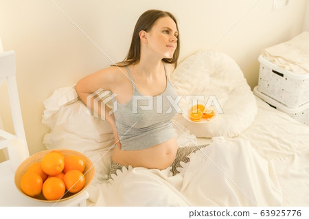 Portrait of young beautiful pregnant woman with oranges. Healthy food, natural vitamins 63925776