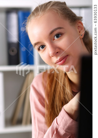 Workplace girl peeks out from behind monitor Workplace girl peeks out from behind monitor 63930133