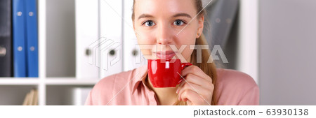 Girl sits office front computer and drinks coffee 63930138