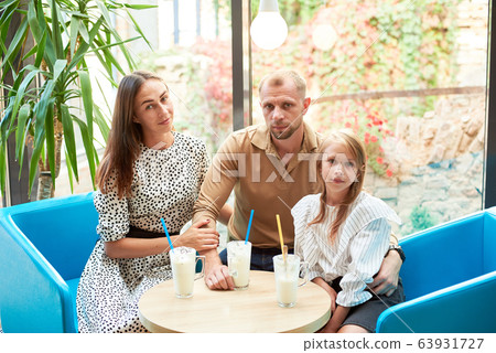 Friendly family having milkshakes in the cafe 63931727