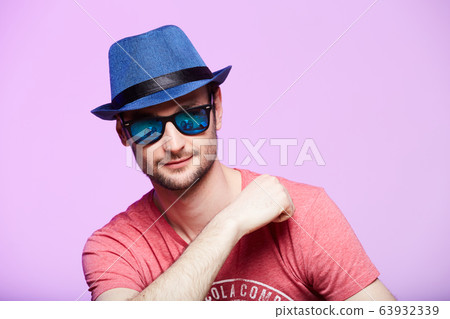 Young hipster man wearing blue hat. Studio shot over pink background. Young hipster man wearing blue hat. Studio shot over pink background. 63932339