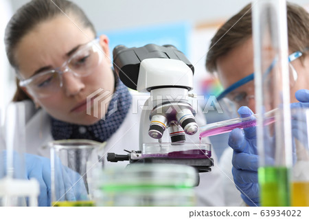 People look at reaction liquid under microscope. People look at reaction liquid under microscope. 63934022