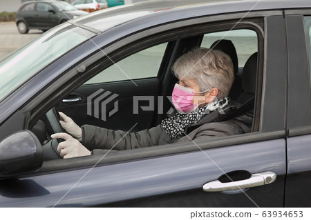 Protected female driver in car wearing mask and Protected female driver in car wearing mask and 63934653