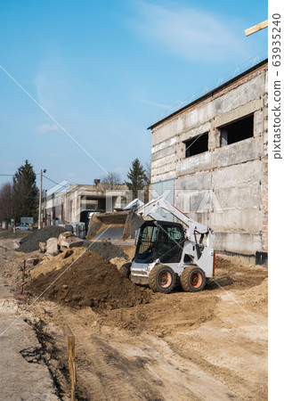 White skid steer loader at a construction site working with a soil. Industrial machinery. Industry. 63935240