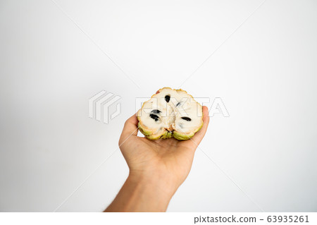 Female hand holding a three ripe sweetsop custard apple on a white background. 63935261