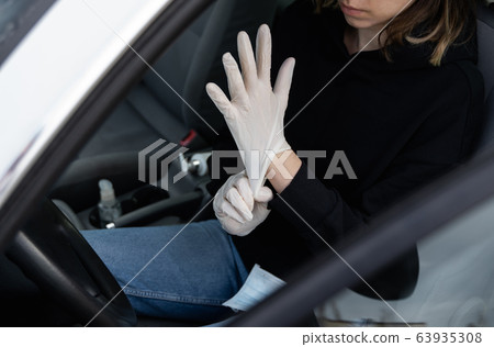 Woman in protective medical mask is wearing rubber gloves for protect himself from bacteria virus while planning to drive. Protective mask while quarantine, pandemic, covid 19, coronavirus, infection. Woman in protective medical mask is wearing rubber gloves for protect himself from bacteria virus while planning to drive. Protective mask while quarantine, pandemic, covid 19, coronavirus, infection. 63935308