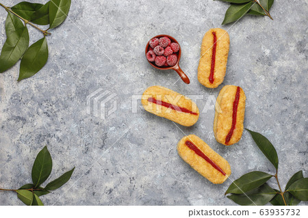 Puff pastry cookies with raspberry jam and frozen raspberries on light background 63935732