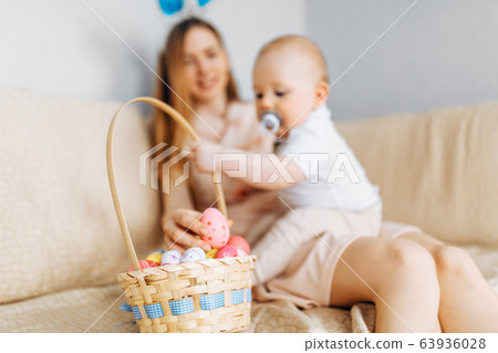 Mother and baby with rabbit ears, with Easter eggs 63936028