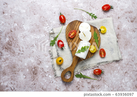 Goat Cheese Slices on Wooden Board with ruccola,cherry tomatoes. Ready to Eat. Goat Cheese Slices on Wooden Board with ruccola,cherry tomatoes. Ready to Eat. 63936097