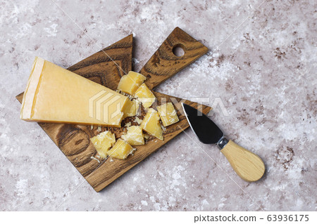 cheese board with hard cheese ,cheese knife,red wine glass,grape on brown concrete background 63936175