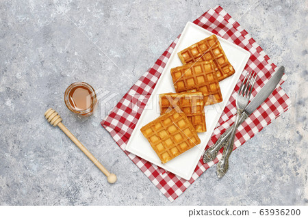 Traditional belgian waffles with fresh berries and honey on grey concrete background. Flat lay, top view, copy space. 63936200