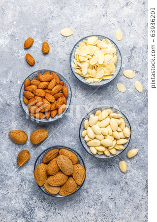 Raw fresh almonds with shell,without shelll,almond slices on grey concrete background,top view Raw fresh almonds with shell,without shelll,almond slices on grey concrete background,top view 63936201