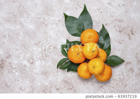 Tangerines (oranges, clementines, citrus fruits) with green leaves on concrete background with copy space 63937219