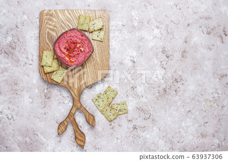 Beetroot hummus on cutting board with salty cookies on light background 63937306