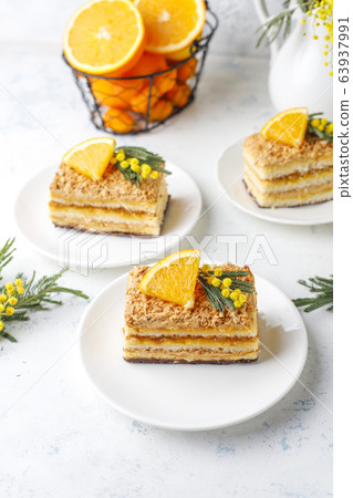 Orange cake decorated with fresh orange slices and mimosa flowers on light background Orange cake decorated with fresh orange slices and mimosa flowers on light background 63937991