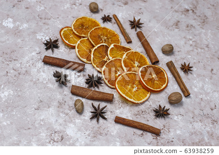 Organic homemade dried orange chips slices,nuts,star anise,cinnamon sticks on light brown background,top view 63938259