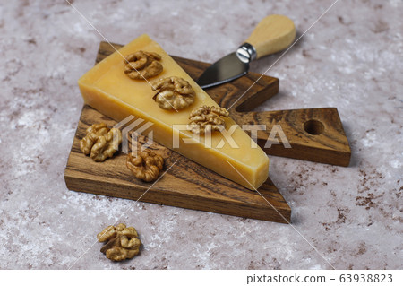 cheese board with hard cheese ,cheese knife,red wine glass,grape on brown concrete background 63938823