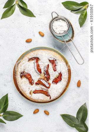 Homemade rustic plum cake with powdered sugar and almond,top view 63938867