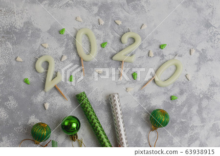 Candles in the shape of numbers 2020 as a symbol of the new year next to christmas shaped sparkle candies on a gray table. Top view, flat lay 63938915