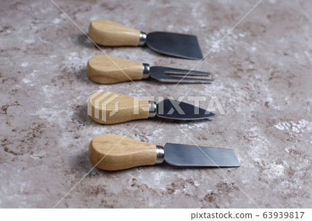 Cheese knives with wooden handles, fork, spatula on light brown background,top view. 63939817