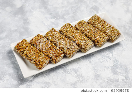Granola bar. Healthy sweet dessert snack. Sesame, peanut, sunflower in honey. Gozinaki is Georgian national food, oriental sweet. Top view on concrete background 63939978