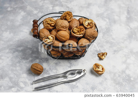 Whole walnuts in shell in food metal basket, walnut kernels. Top view on concrete background 63940045
