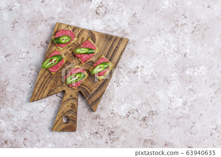 Beetroot hummus canapes withgreen pepper slices and parsley on cutting board on light background 63940635