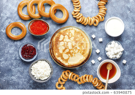 Shrovetide Maslenitsa festival meal. Russian pancake blini with raspberry jam, honey, fresh cream and red caviar,sugar cubes,cottage cheese,bubliks on dark background 63940875