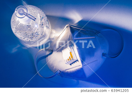 Anti-septic hand gel and N95 mask on white table, dramatic lighting 63941205