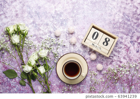 March 8 Women's Day card with white flowers,sweets and a cup of tea on light background. 63941239