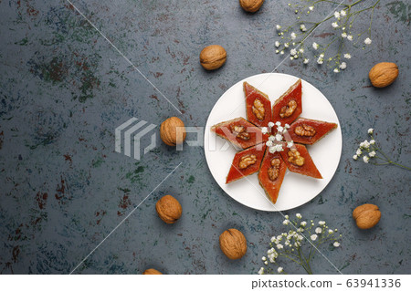 Azerbaijan national pastry pakhlava on white plate on dark background ,top view,spring new year celebration Novruz holiday. Azerbaijan national pastry pakhlava on white plate on dark background ,top view,spring new year celebration Novruz holiday. 63941336