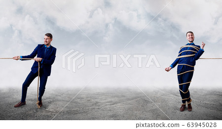 Angry businessman pulls tied himself with a rope. 63945028