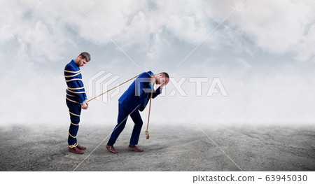 Upset businessman pulls tied himself with a rope. 63945030
