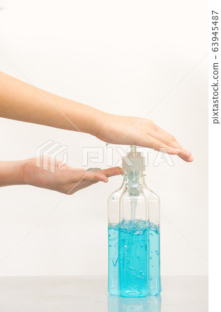 Female hands using hand sanitizer gel pump 63945487