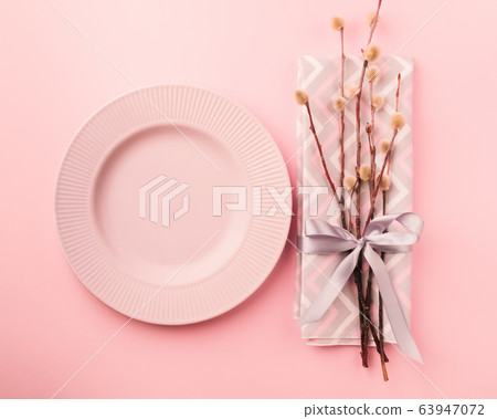 Empty plate of pussy-willow twig festive napkin tied with a satin ribbon with a bow on a pastel pink background. 63947072