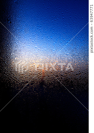 Drops of water on a glass in blue in the morning. Drops of water on a glass in blue in the morning. 63947771