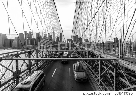 Traffic in rush hour after working day on the Brooklyn bridge over New York cityscape background with sunset, USA, United States, Business and transportation concept Traffic in rush hour after working day on the Brooklyn bridge over New York cityscape background with sunset, USA, United States, Business and transportation concept 63948080